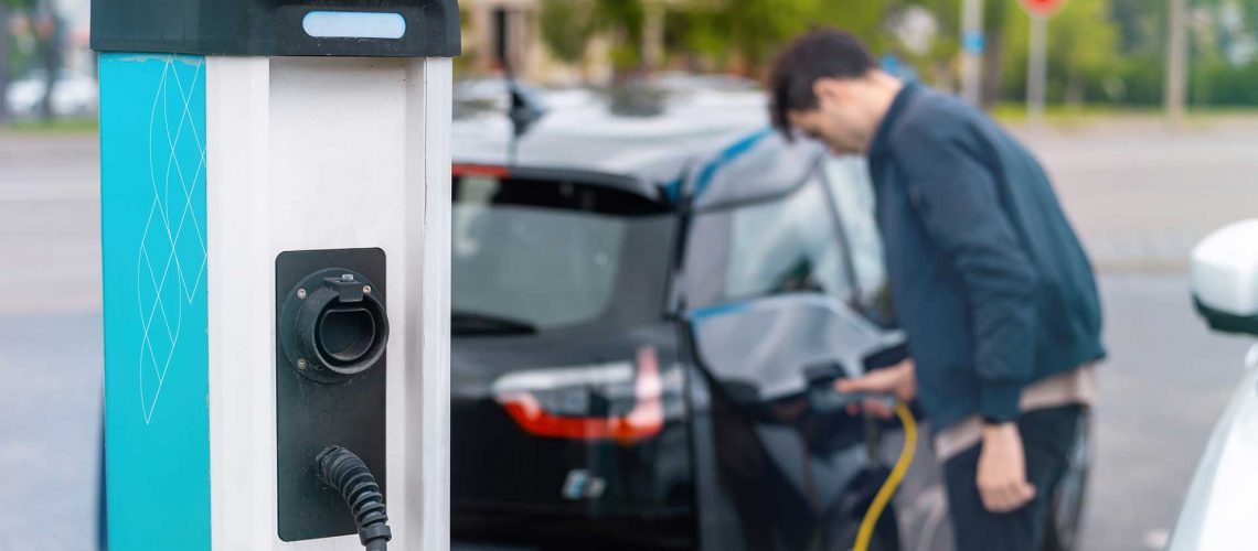 man-plugging-charger-into-electric-car-charge-station